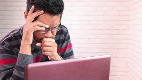 man experiencing discomfort while working on a laptop