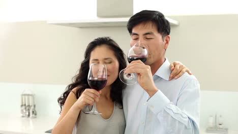 couple drinking red wine and smiling at camera