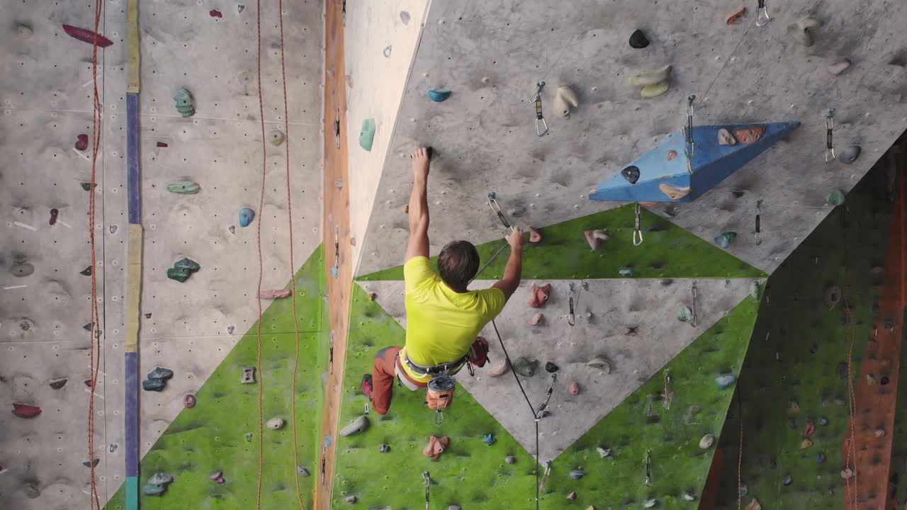 Young Woman Rock climber is Climbing At Inside climbing Gym. slim pretty Woman Exercising At Indoor Climbing Gym Wall