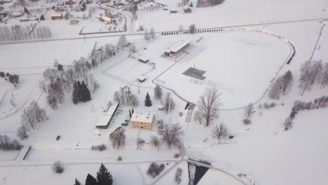 snow covered soccer field and stadium seats, bird`s eye view, snowy winter day