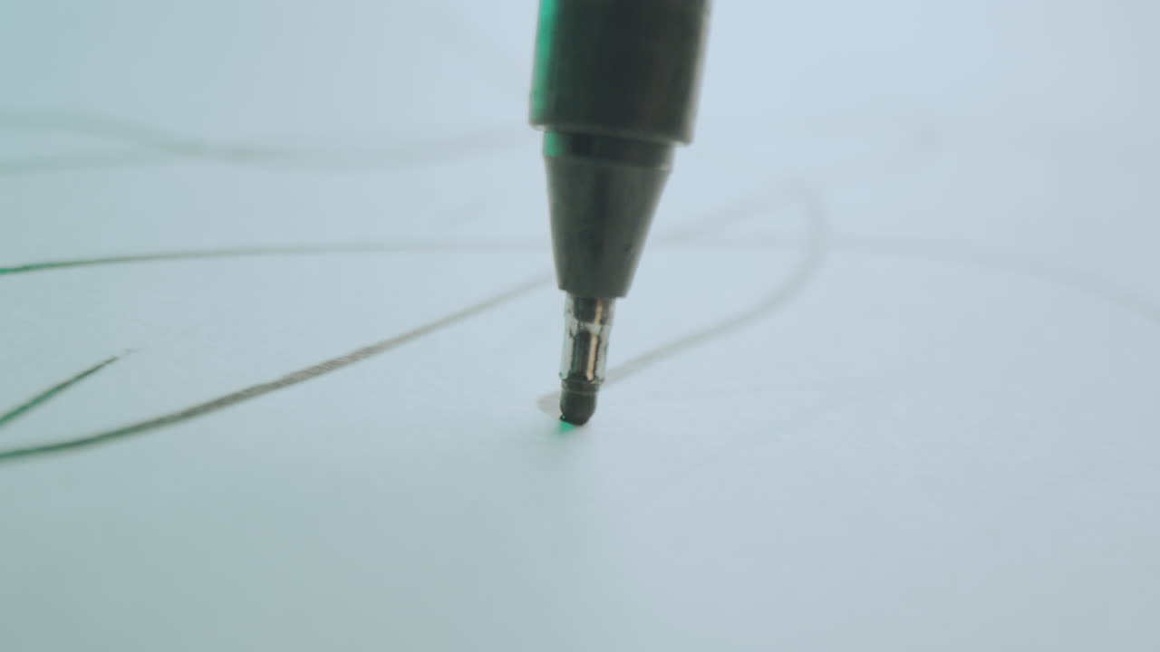 Close-up of a pen drawing lines on paper