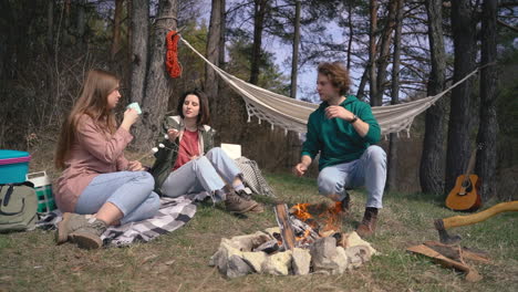 two young girls and a young boy make a bonfire in the forest 1