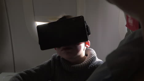 en el avión se sienta un niño pequeño con gafas de realidad virtual