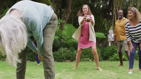 animación de felices y diversas mujeres y hombres amigos mayores jugando al fútbol americano en el jardín