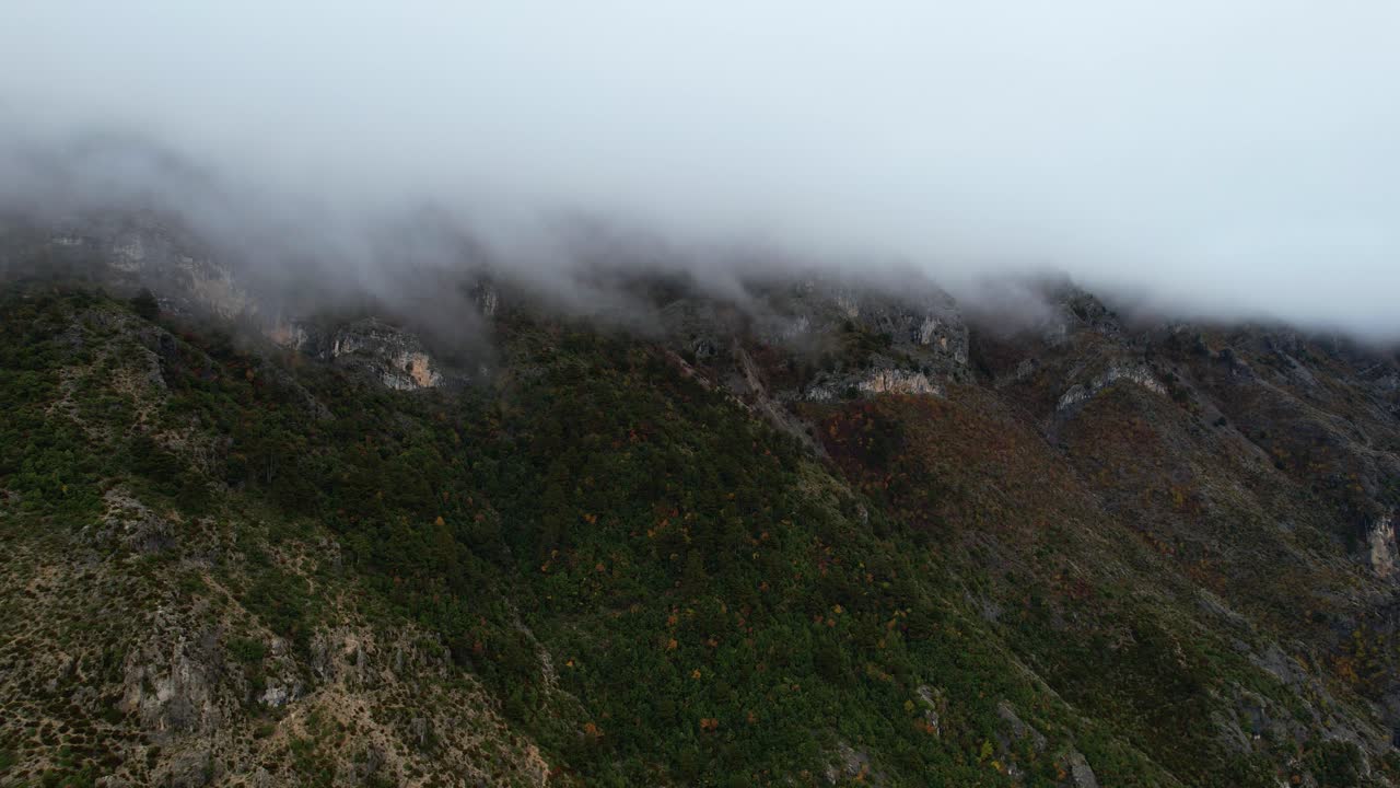 cielos de otoño dramáticos: nubes que envuelven montañas brumosas con movimientos dinámicos en un terreno áspero, escena atmosférica