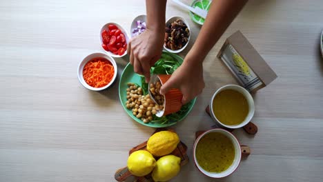 Adding-chick-peas-Aerial-shot-making-of-a-salad-adding-tomatoes-carrots-spinach-chick-peas-lemons-onions-nuts-dressing-in-view