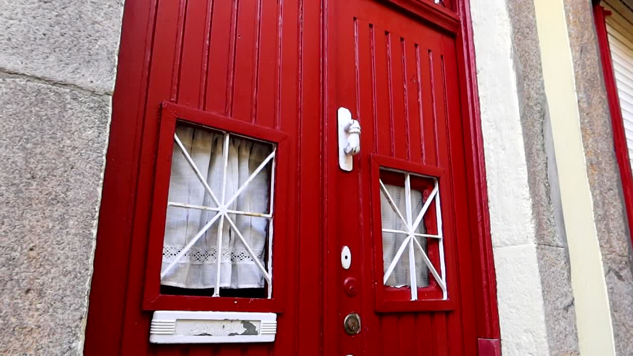 cerca de una puerta roja vintage con detalles blancos y un golpeador en forma de puño