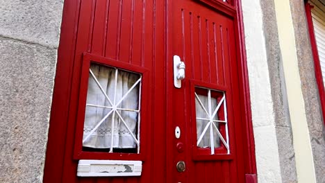 Close-up-of-a-vintage-red-door-with-white-details-and-a-knocker-in-the-shape-of-a-fist