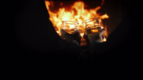 two men are drinking strong alcohol by the fireplace in the frame are visible hands with glasses aga