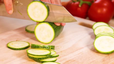 cortar pepinos con un cuchillo, tomates en el fondo