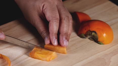 hands carefully slicing a ripe persimmon