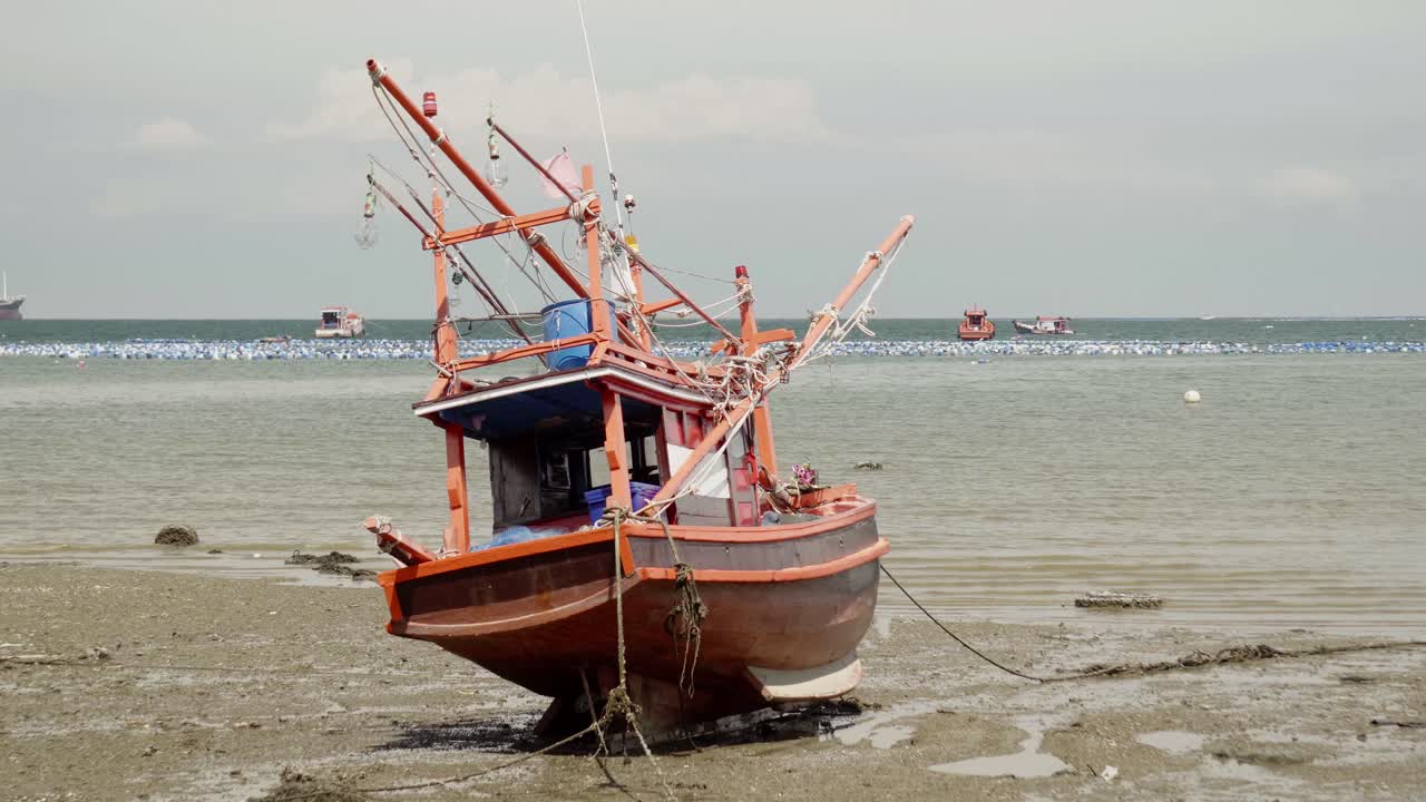 una imagen inclinada hacia abajo de un barco de pesca de calamar varado amarrado durante la marea baja en tailandia