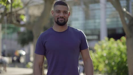 medium shot of young man in park looking at camera, smiling