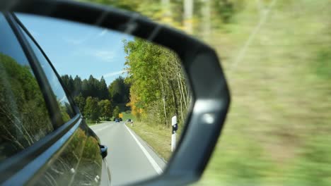 Vista-De-Cerca-De-La-Carretera-En-El-Espejo-Retrovisor-De-Un-Coche