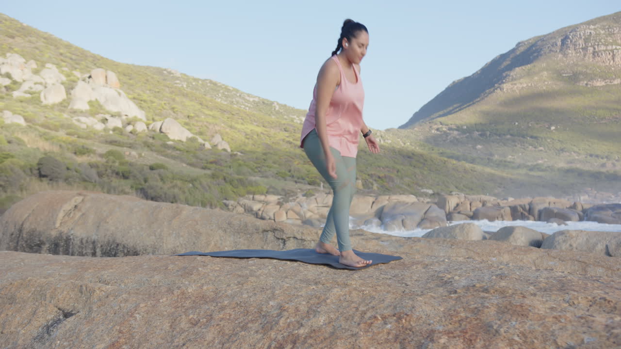 Practicing yoga, mature asian woman standing on yoga mat in serene outdoor setting, copy space