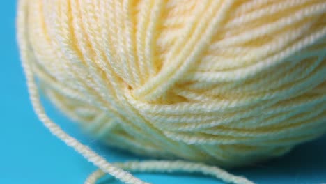 close-up-of-yellow-wool-yarn-ball-on-blue-background