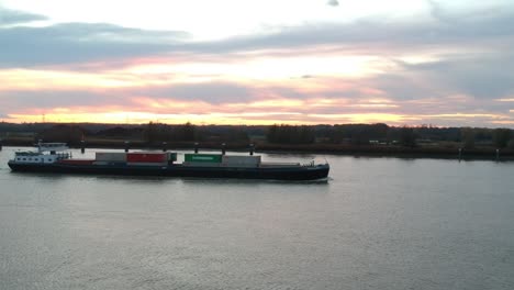 drone pushes towards a freight ship with the golden-red sunset on the horizon