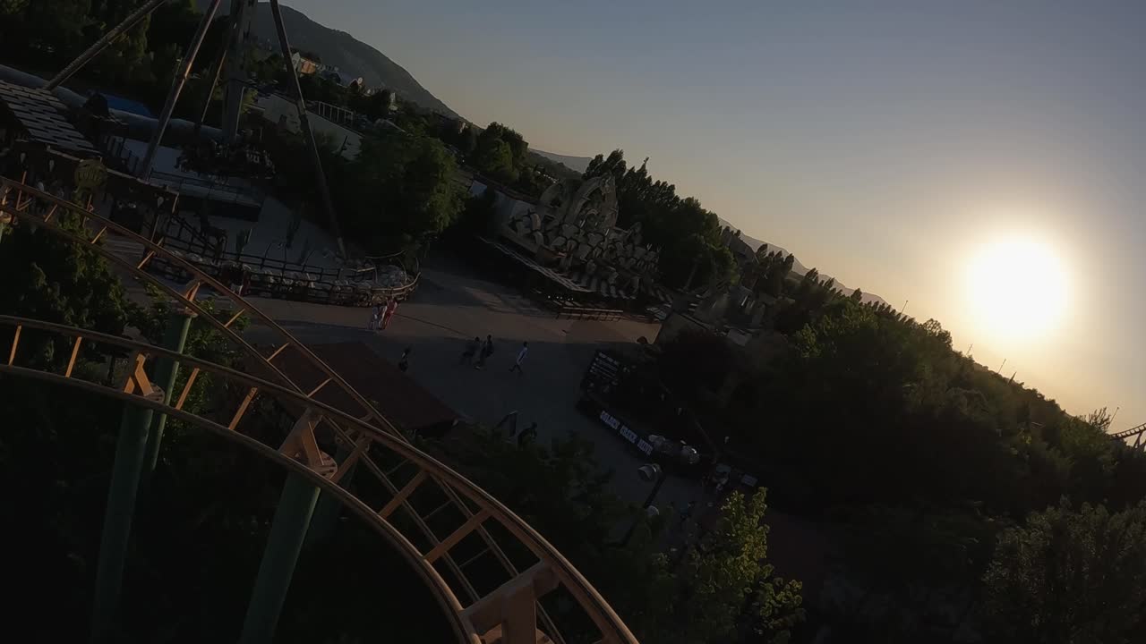 vista en primera persona de la montaña rusa de adrenalina en el parque de atracciones al atardecer