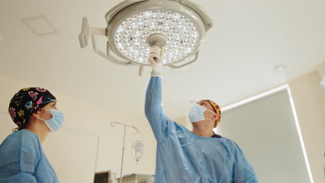 cirujanos ajustando las luces de la sala de operaciones