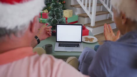 Back-view-of-caucasian-senior-couple-using-laptop-with-copy-space-at-christmas-time