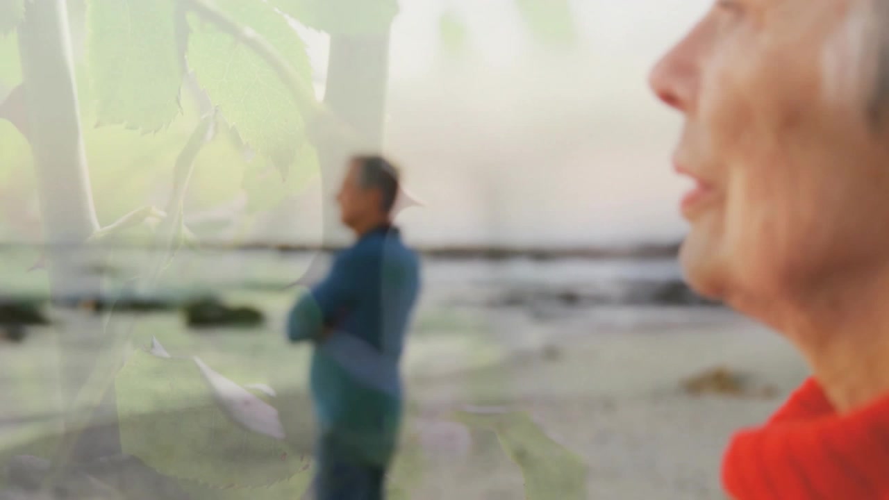 senior woman breathing on beach health leaves drifting, camera shifting revealing man behind