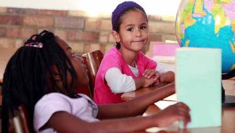 Cute-schoolchildren-reading-and-looking-at-globe-in-their-classroom