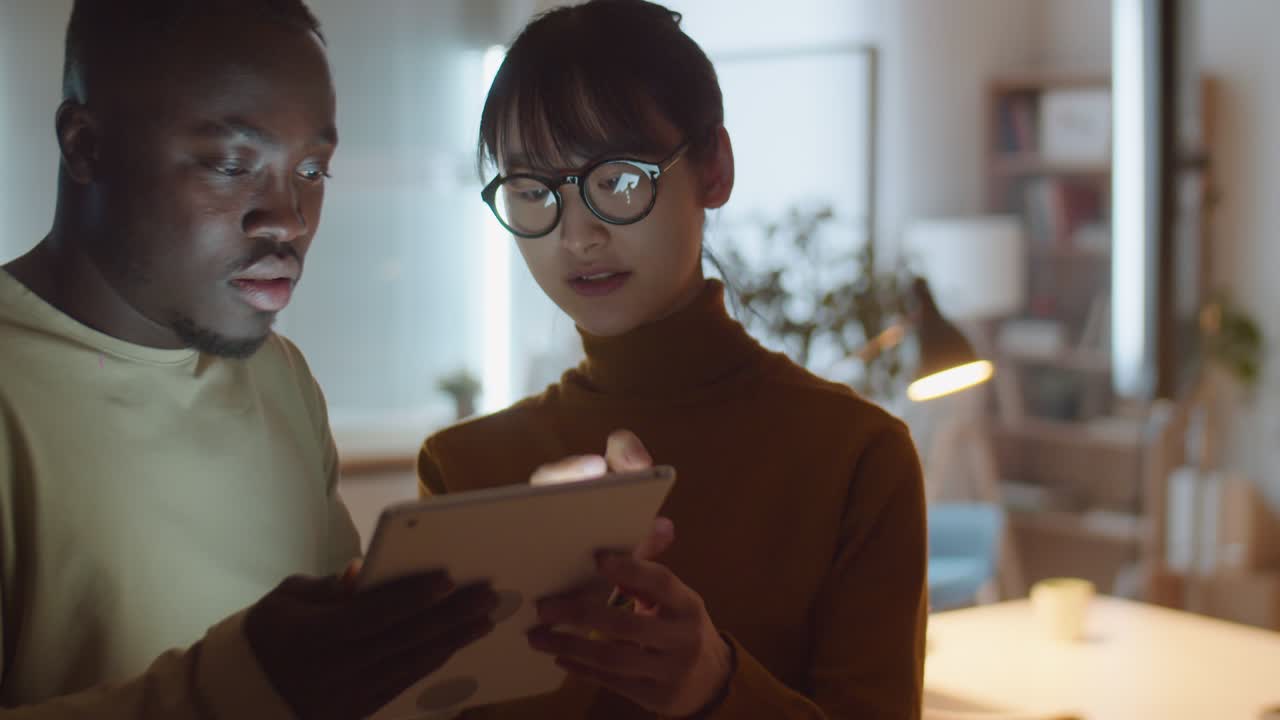 Multiethnic Colleagues Working on Digital Tablet in Office at Night