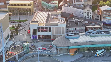 Drone-ascend-tilt-down-along-downtown-city-center-of-Barnsley-as-golden-light-glow-spreads-across-buildings