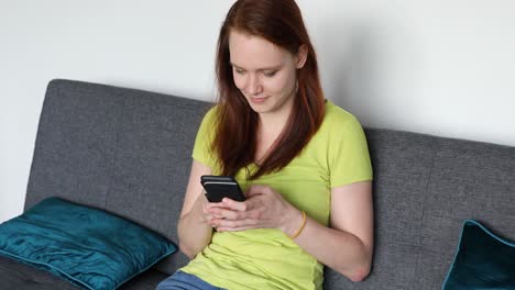 woman sitting on the sofa in the living room and talking on the smartphone