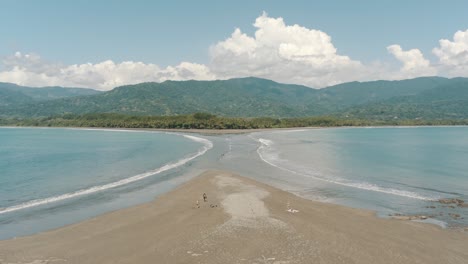 vuelo cercano con drone sobre la orilla de la playa con forma de cola de ballena en costa rica