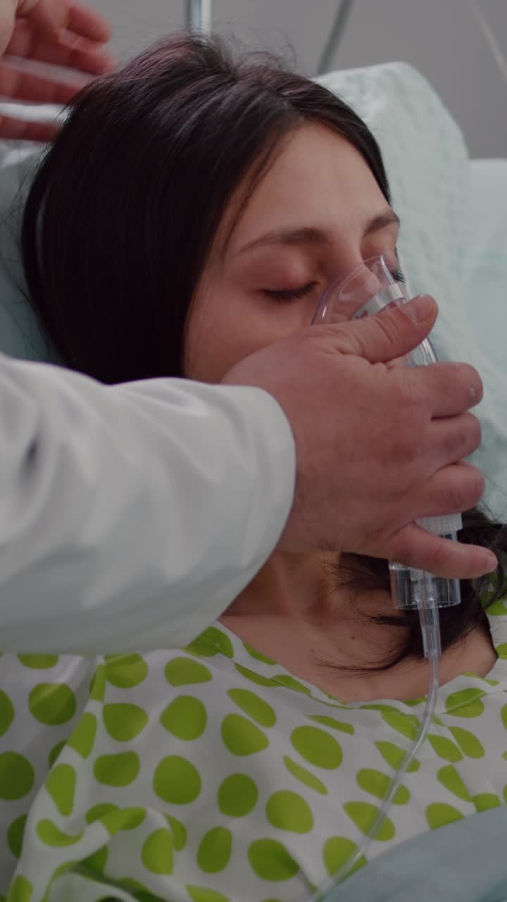 Vertical video: Close up of medical doctor putting oxigen mask to sick woman