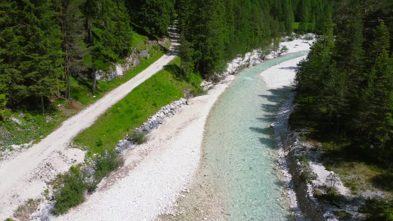 Fiume naturale incontaminato circondato da un paesaggio verdeggiante nelle Dolomiti italiane in estate, vista aerea.