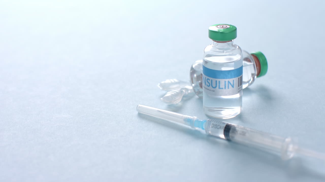 Close up of insulin vials and syringe on blue background with copy space, slow motion