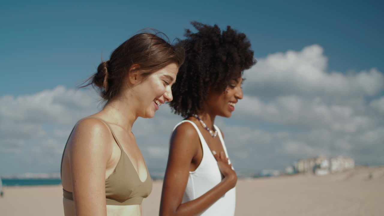 Ragazze rilassate che vanno in spiaggia alla luce del sole, in primo piano. Amiche attraenti ad un appuntamento.