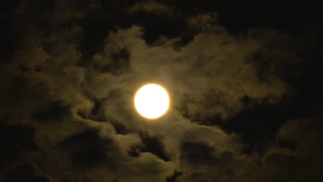 luna amarilla o sol visto a través de manchas de nubes oscuras que se mueven en el viento