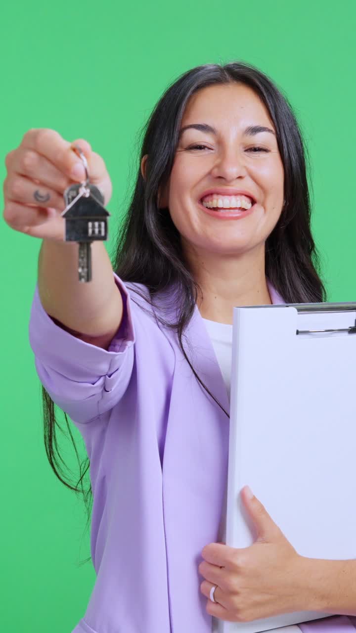 Agente inmobiliario mostrando llaves de casa nueva en pantalla verde
