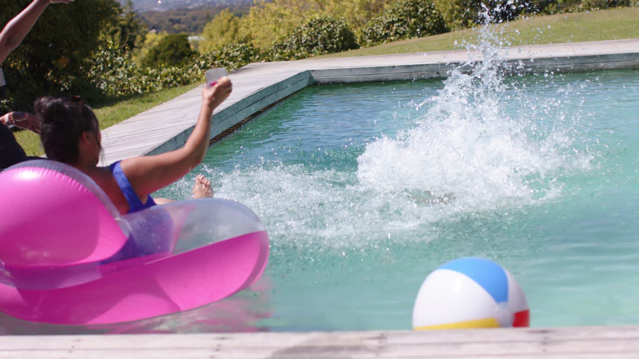 Jumping Senior in black one-piece suit diving into pool after friends cheer, pink float, copy space