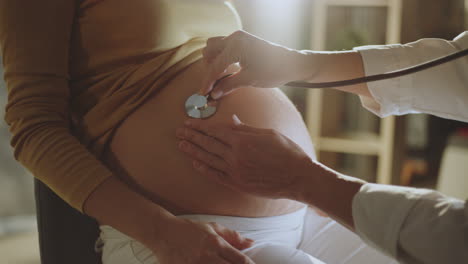 doctor examining pregnant woman's belly with stethoscope
