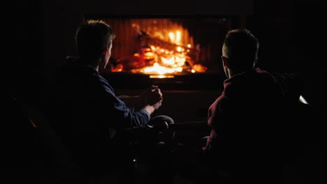 friends rest at home by the fireplace and a man plays the guitar