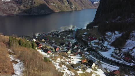 looking down hillside at vi small remote village undredal by the sea - aerial norway at winter sunrise