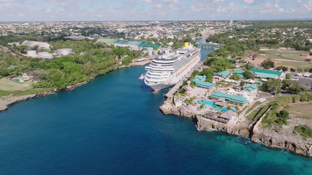 Large cruise ship moored in port of La Romana, Dominican Republic, cityscape in the background. Aerial drone