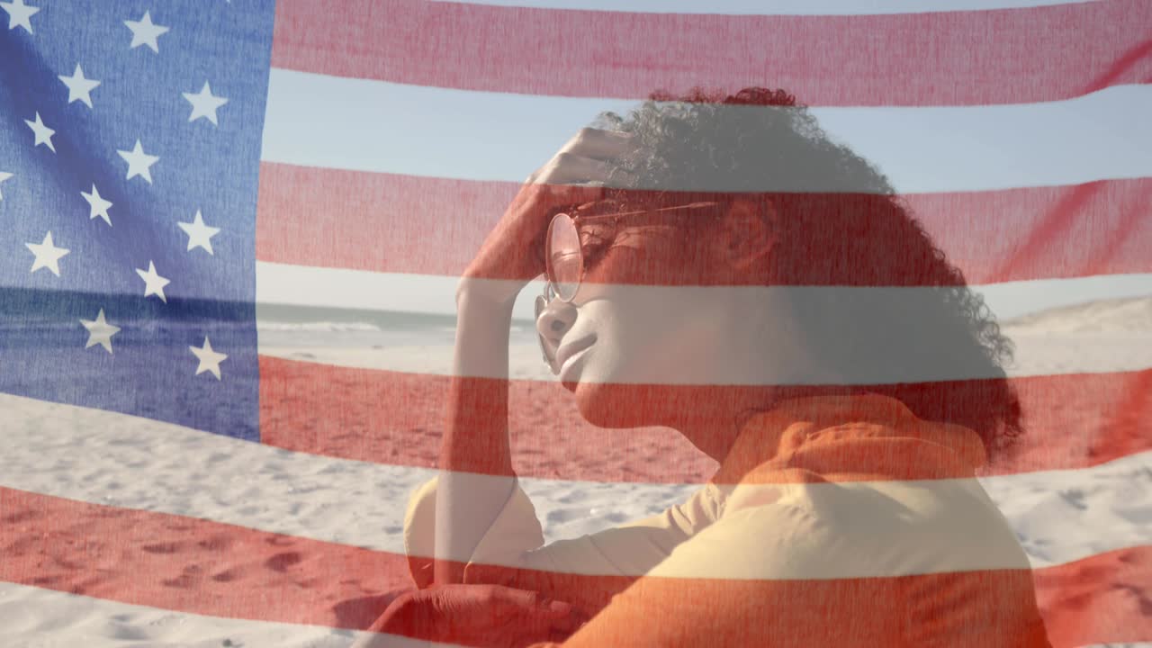 海辺のビーチに座っているサングラスをかけた女性の上にアメリカ国旗がはためくアニメーション