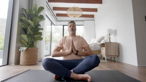 senior biracial man practicing yoga meditation at home