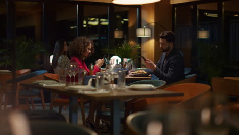 busy couple texting phone mobile device on evening restaurant dinner date.