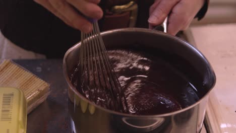 baker whisks chocolate in large mixing bowl