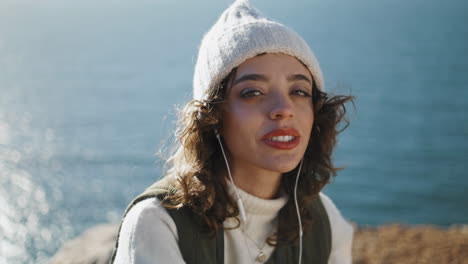 portrait ocean girl listening music in earphones vertical. traveler look camera