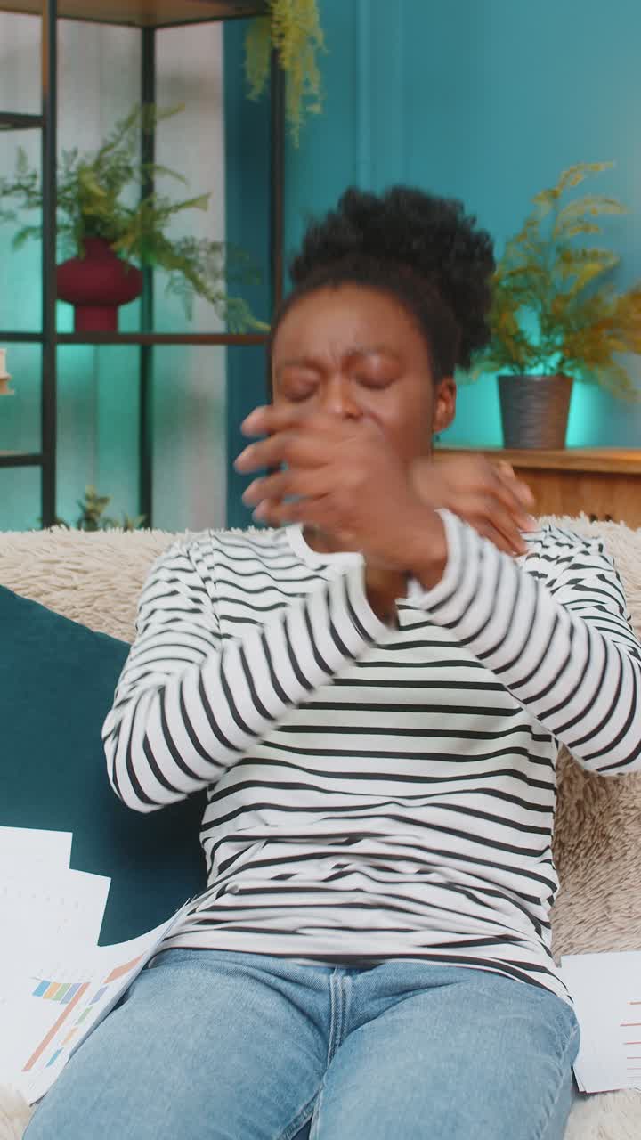 Donna afroamericana turbata e stressata per problemi finanziari, seduta a casa a guardare i documenti