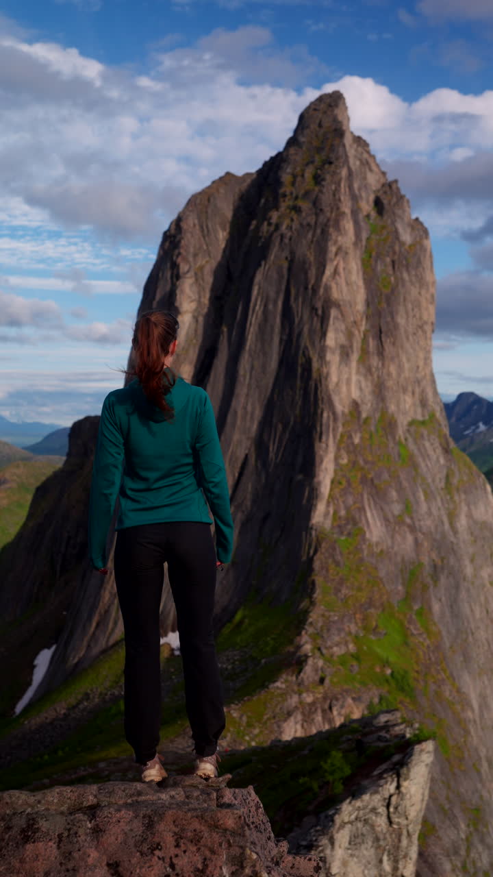 Rear view of female traveler in awe of precipitous Segla mountain. Vertical