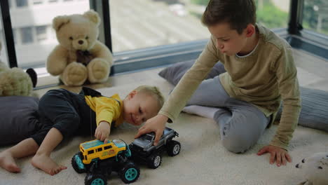 Two-siblings-enjoying-indoor-games.-Beautiful-kids-playing-toy-monster-trucks.