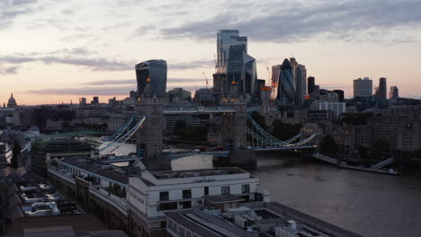 Evening-sliding-view-of-Tower-Bridge-and-modern-skyscrapers-in-financial-and-economical-hub.-Colourful-sunset-sky.-London,-UK